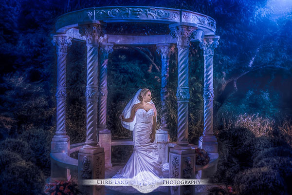 Wedding picture of a couple under a pier at Wrightsville Beach looking out to the Atlantic Ocean. Beach wedding photography