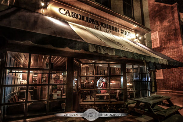 A romantic wedding picture of newlyweds on a counch outside at night lit by a chandelier hanginf form a tree.  Wedding picture ideas.